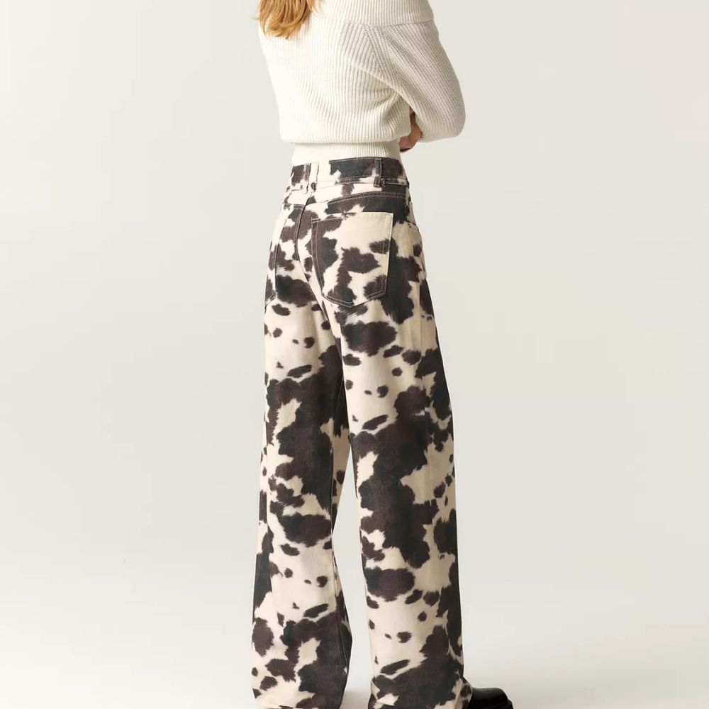 Person wearing cow print pants on a plain background