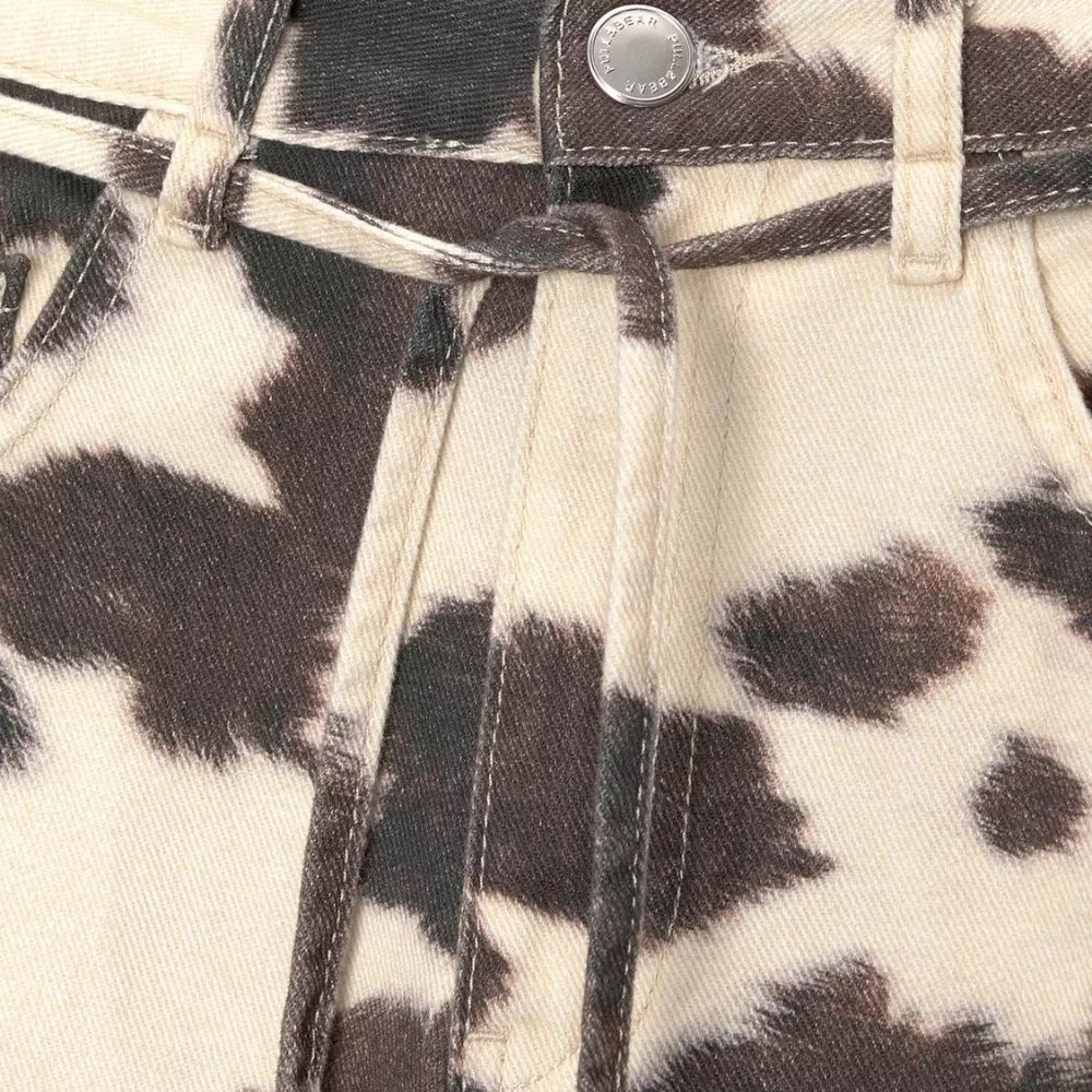 Close-up of a denim jacket with a cow print pattern