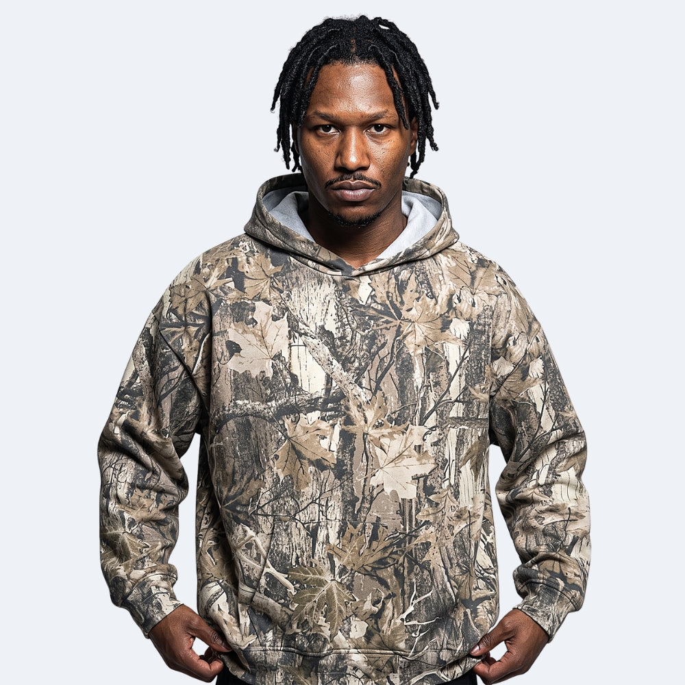 Birch. A man wearing a camouflage hoodie with a realistic leaf and branch pattern in shades of brown, beige, and gray.
