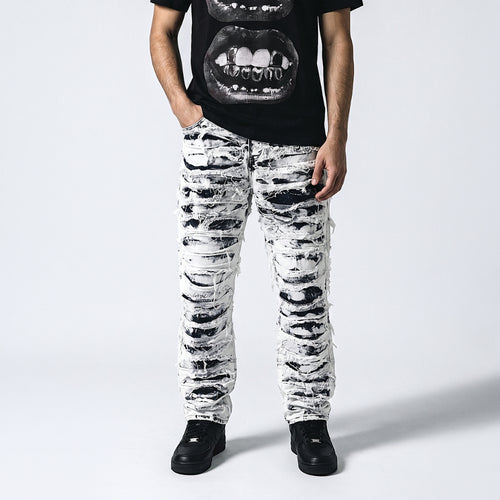 KRUX Shattered Ice denim pants in distressed black and white, worn with a black graphic tee