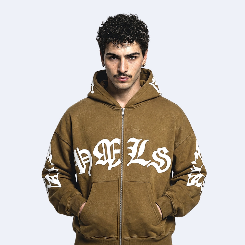 A man wearing a brown zip-up hoodie with white Gothic lettering on the front and sleeves, set against a solid light gray background.