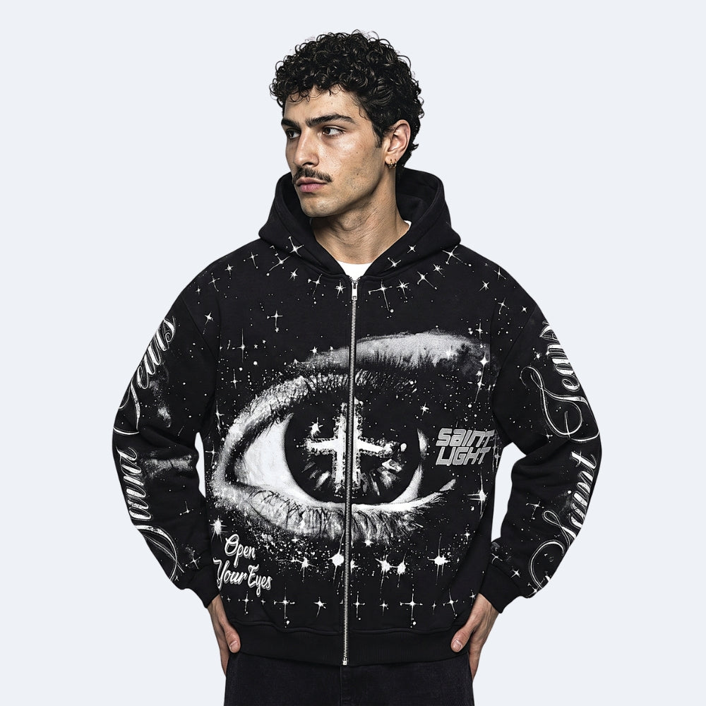 Black. A man wearing a black zip-up hoodie with a large white eye graphic and starry print on the front and sleeves.