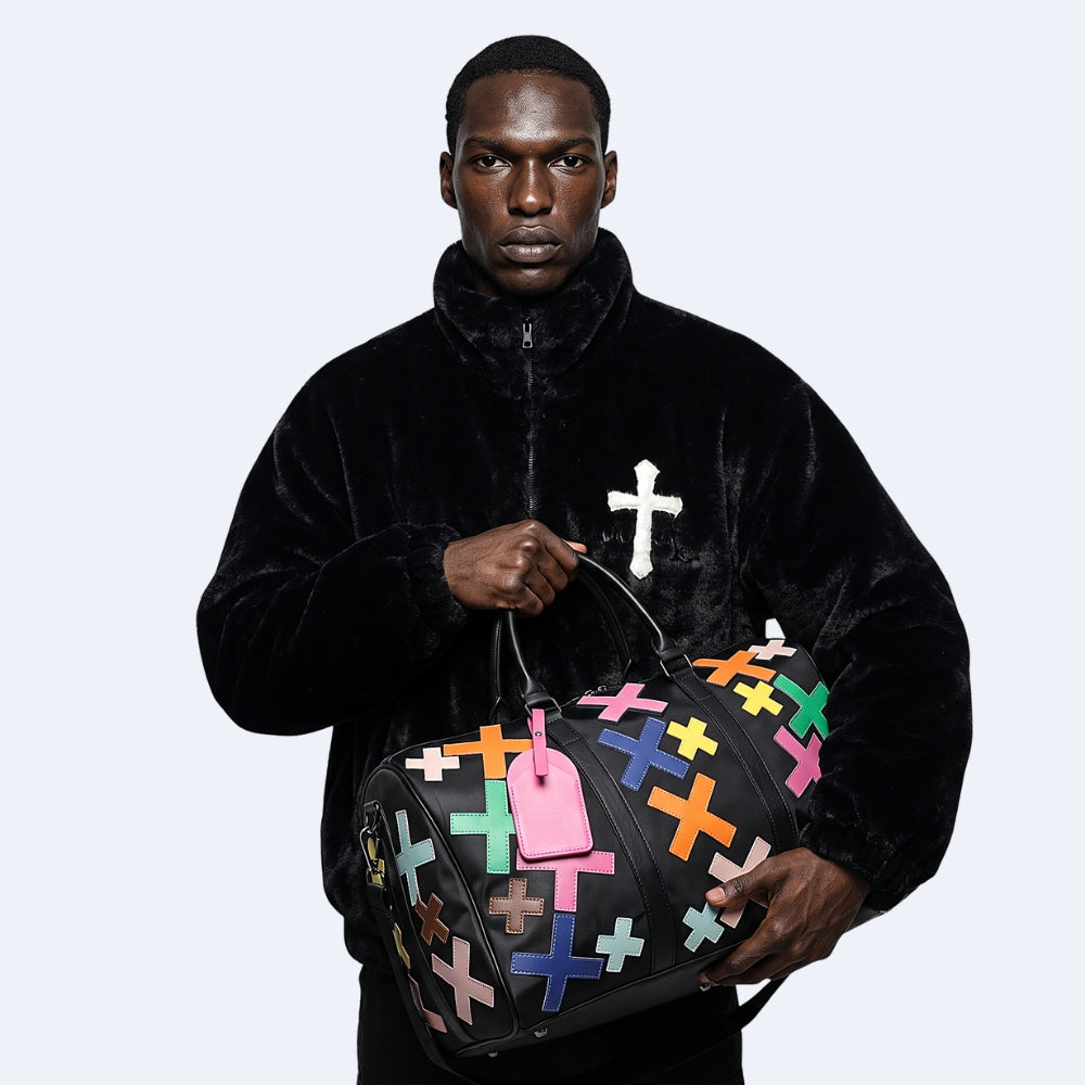 Multicolor. KRUX Crossover duffle bag with colorful cross appliques, held by a model in a velvet jacket