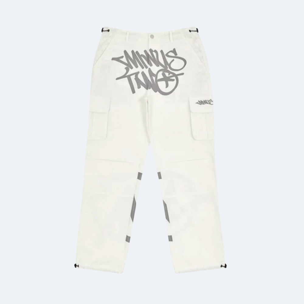 Off-white cargo pants featuring a large gray graffiti-style 'STANKS' logo on the right thigh, a smaller matching logo on the left pocket, and gray reflective striping on the lower legs.