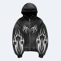 Black. A black zip-up hoodie with a silver zipper, black hood, and ribbed cuffs and hem, decorated with large white tribal flame patterns on the sleeves and chest.