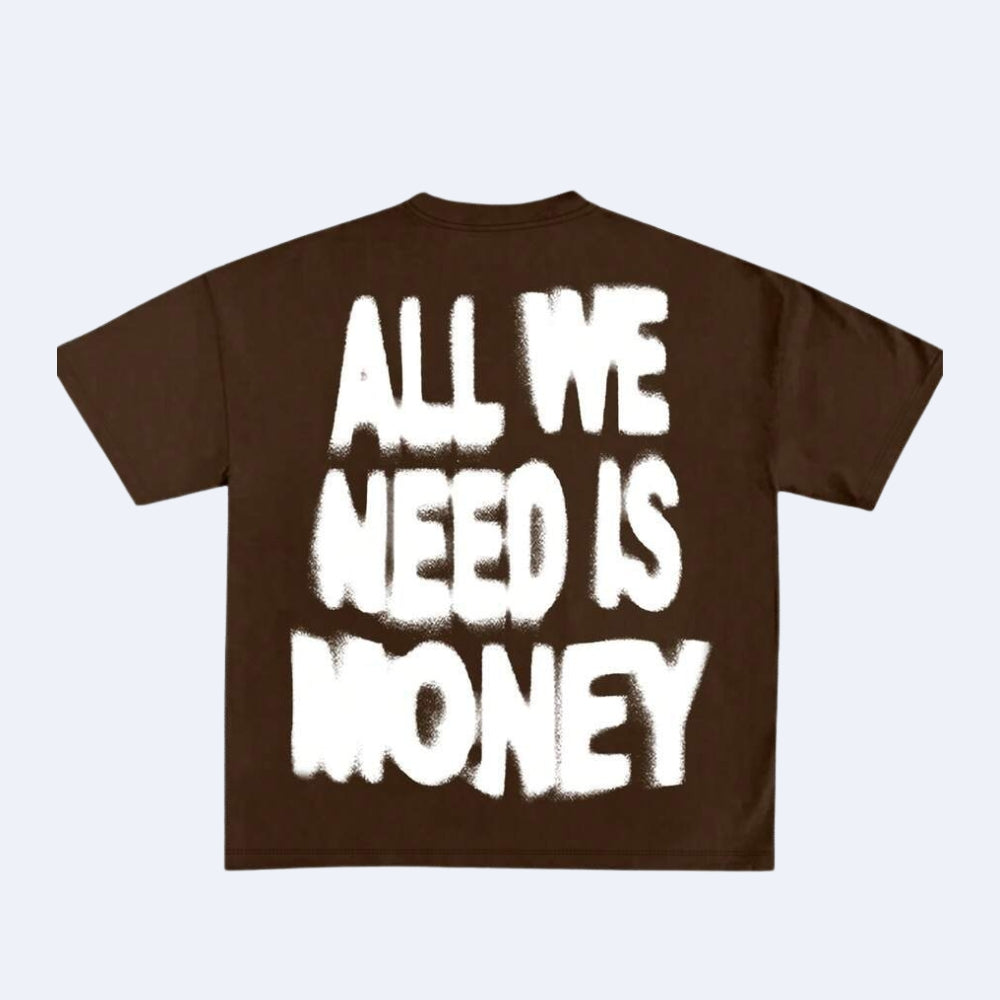 A dark brown short-sleeve t-shirt with the phrase 'ALL WE NEED IS MONEY' printed on the back in a large, white, distressed brush-stroke font, shown against a light gray background.