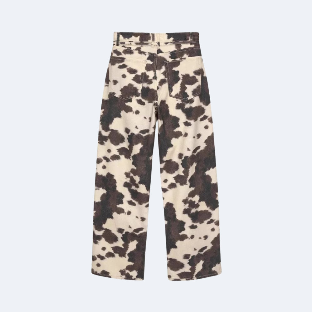 A pair of wide-leg trousers featuring a brown and beige cow-print pattern, displayed flat against a light gray background.