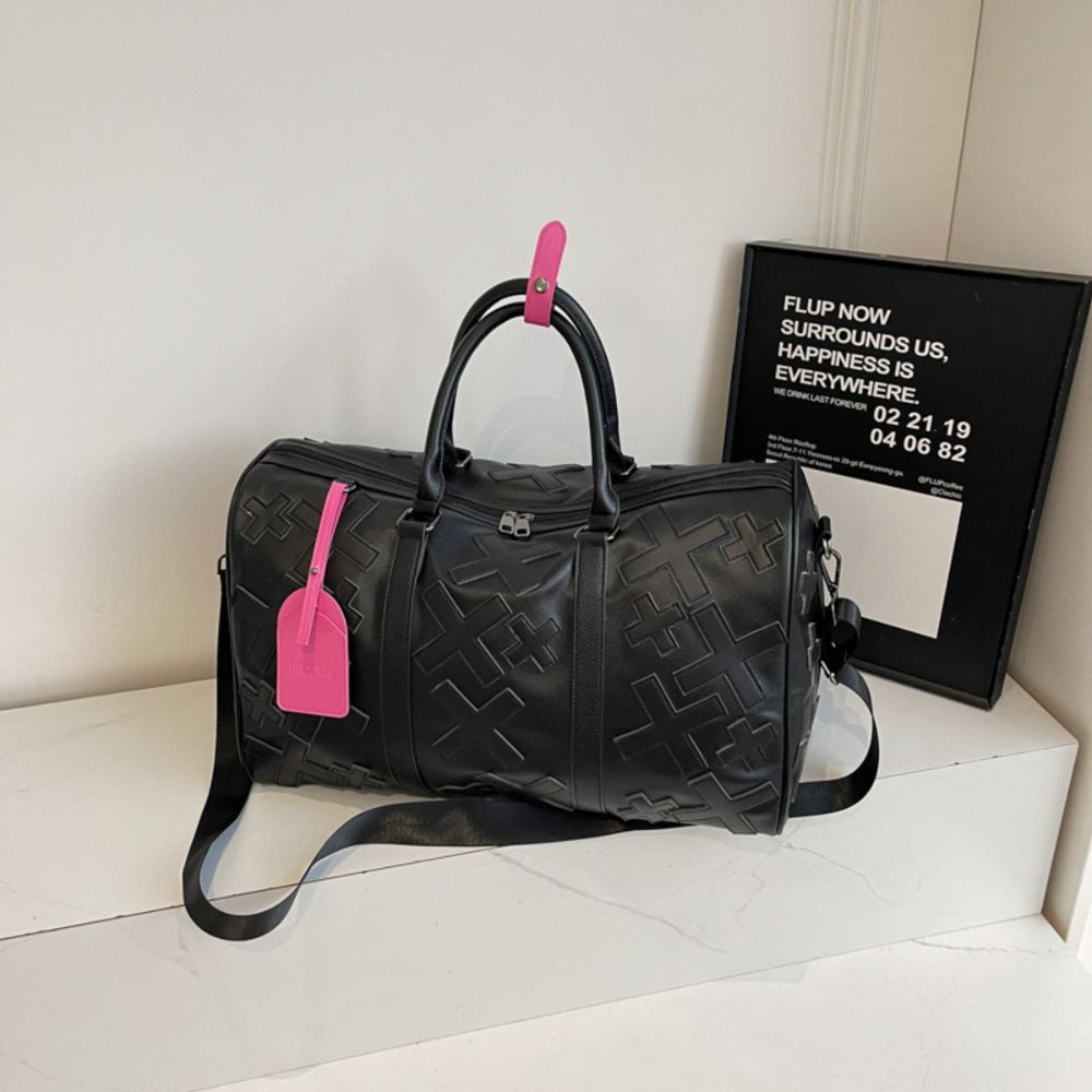 Black. KRUX Crossover duffle bag in black textured leather with pink tags, product view