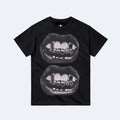Black. A black short-sleeve crewneck t-shirt featuring a graphic print of two overlapping pairs of lips showing teeth, displayed flat.