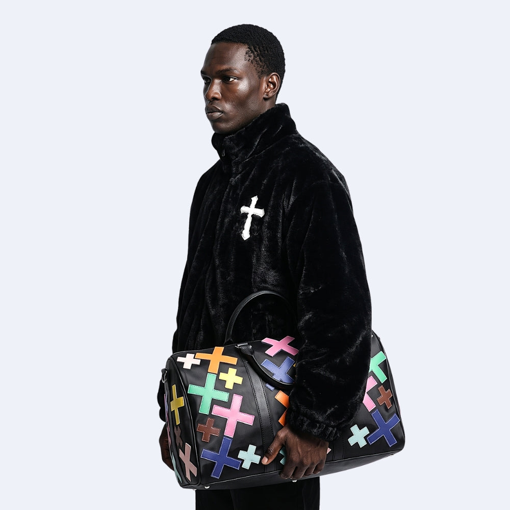Multicolor. KRUX Crossover duffle bag with pink, blue and yellow cross appliques, held by a model