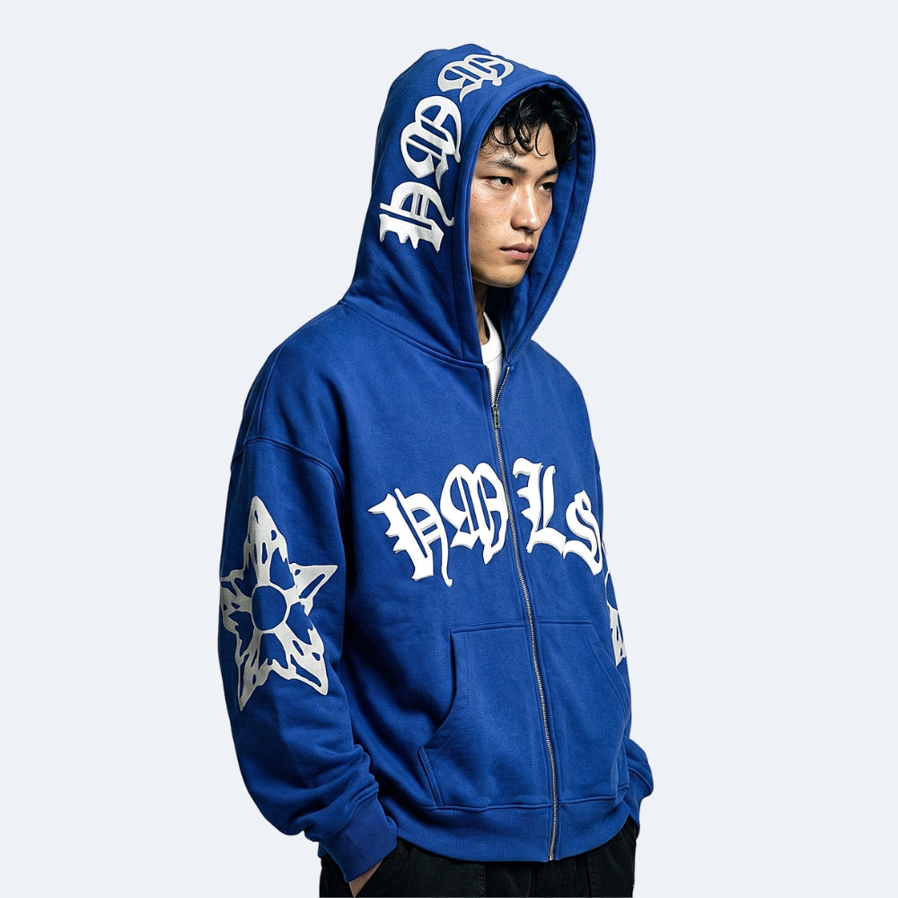 Royal Blue. A man wearing a royal blue zip-up hoodie with white gothic-style lettering and a white star graphic.