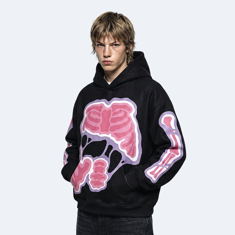 A model wearing a black pullover hoodie with a large pink rib cage graphic on the chest and matching pink arm graphic, set against a light gray background.
