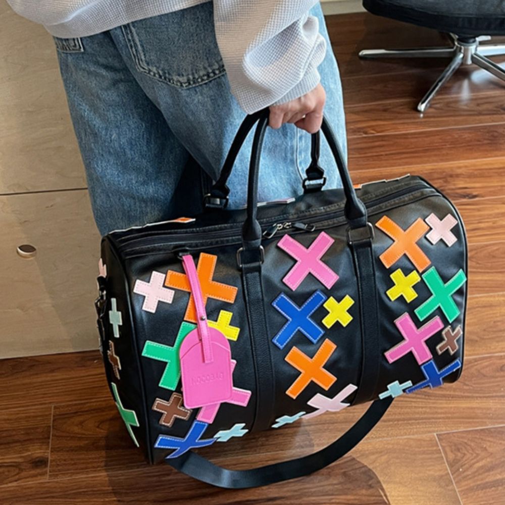 Multicolor. KRUX Crossover duffle bag with colorful X motifs, held by a model on a wooden floor