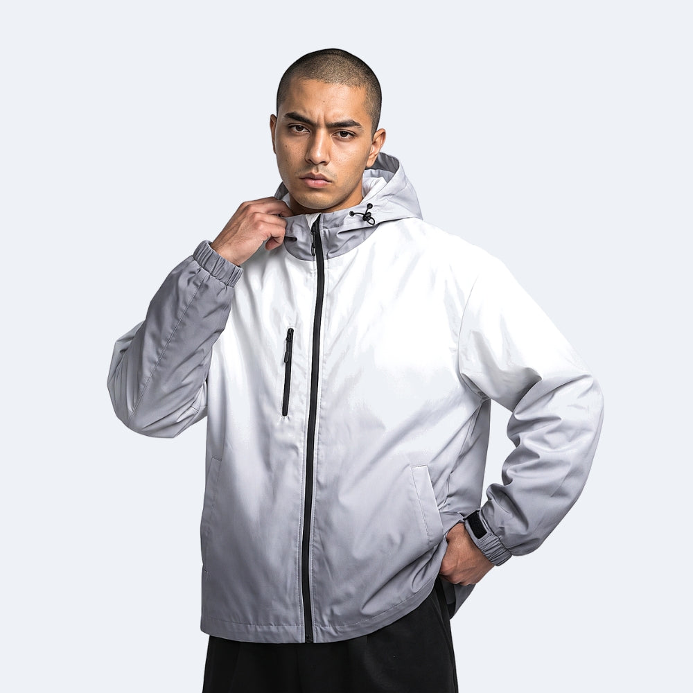Gray. A man wearing a light gray hooded windbreaker jacket with a black zipper.