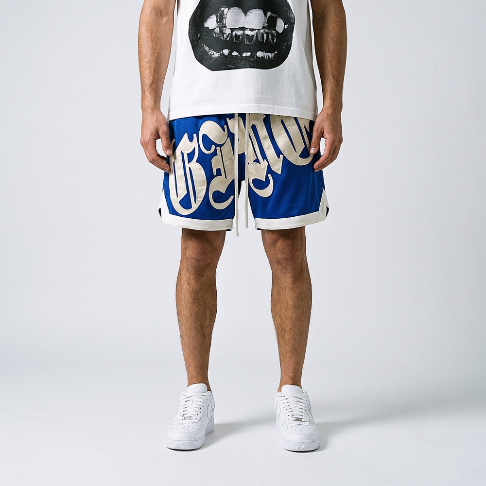 Blue. A model from the waist down wearing blue and white graphic basketball shorts with a white tank top and white sneakers.