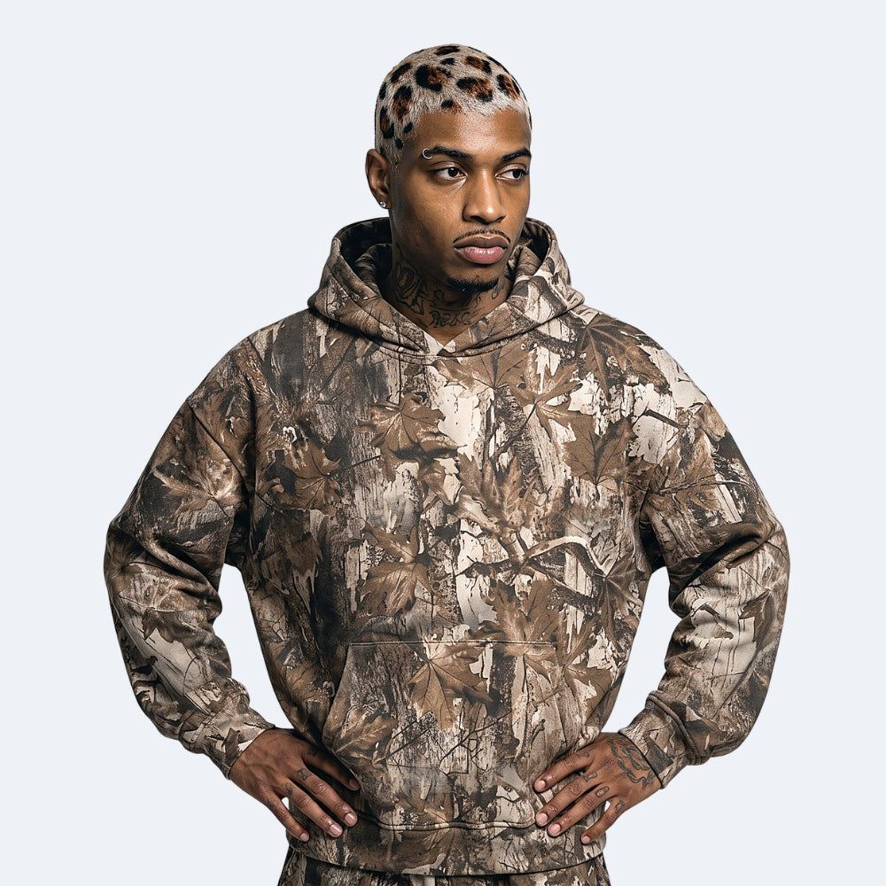 Oak. A man wearing a brown and beige camouflage hoodie with a matching camouflage beanie.
