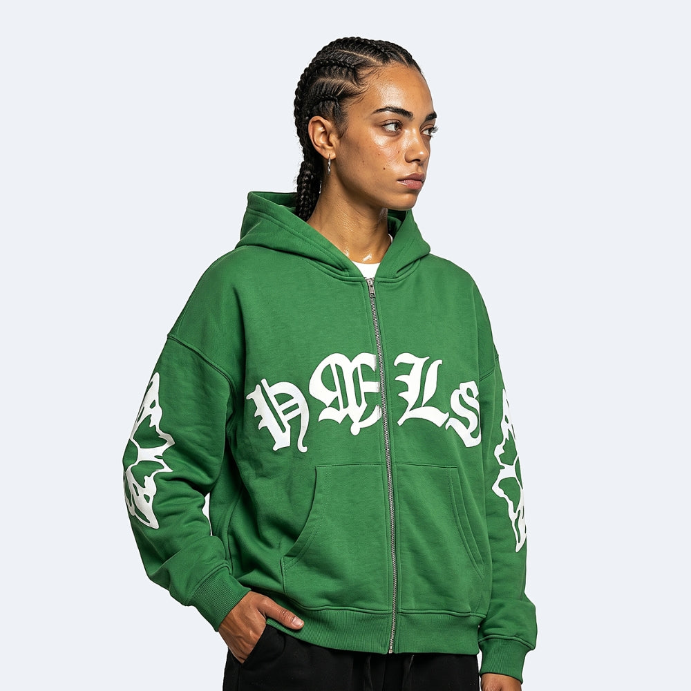 A model wearing a green zip-up hoodie with 'HACLS' printed in a white Gothic font across the chest, and white graphic prints on both sleeves, set against a plain light gray background.