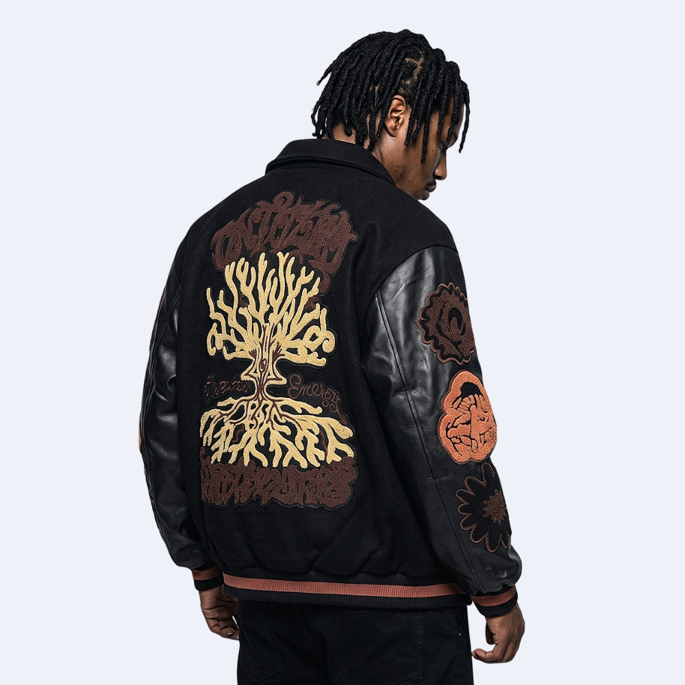 Black. A model from the back wearing a black leather and suede jacket with intricate brown and gold embroidered designs on the back and sleeves.
