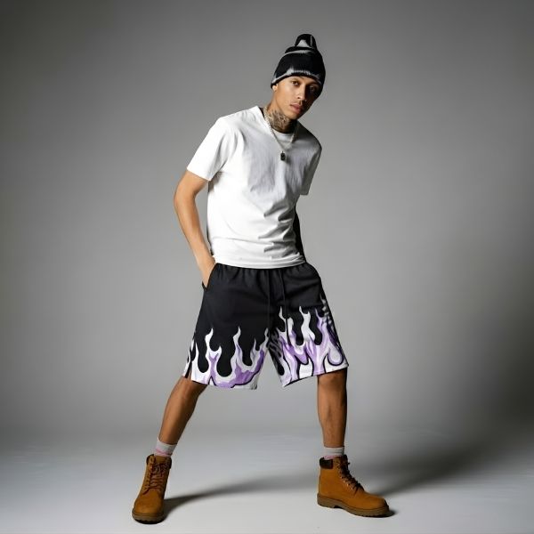 Black. A person wearing a white t-shirt, black shorts with a flame design, and brown boots.