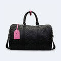 Black. KRUX Crossover duffle bag in black, flat lay with embossed monogram, dual handles and pink tag