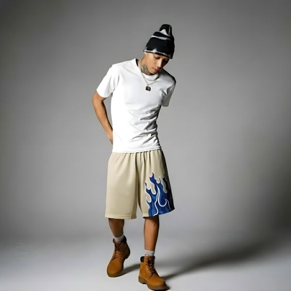Beige. A person wearing a white t-shirt, beige shorts with a blue design, and brown boots.